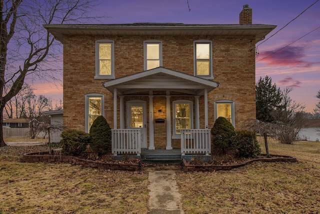 view of front of home featuring covered porch, brick siding, and a chimney