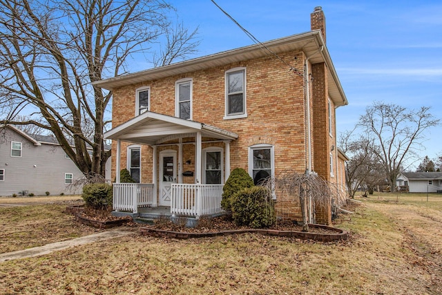 view of front of property with a porch, a chimney, a front yard, and brick siding