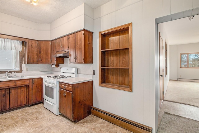 kitchen with under cabinet range hood, a sink, baseboard heating, brown cabinets, and gas range gas stove