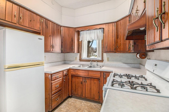 kitchen featuring white appliances, light countertops, a sink, and under cabinet range hood