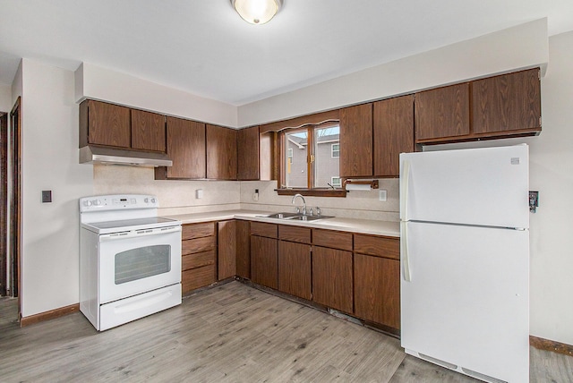 kitchen featuring white appliances, light wood-style floors, light countertops, under cabinet range hood, and a sink