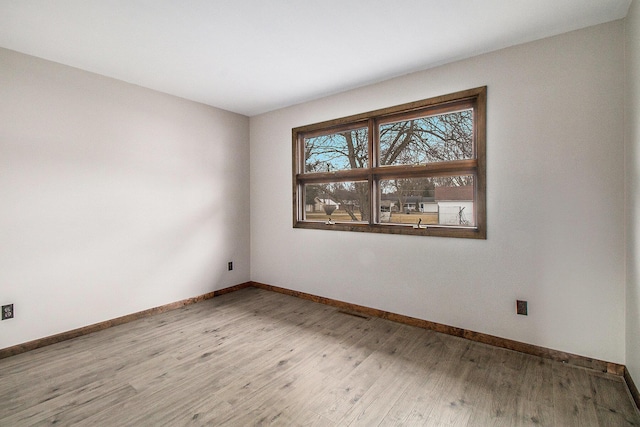 spare room featuring baseboards and wood finished floors