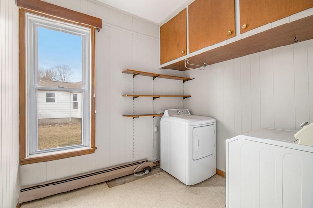 clothes washing area with washer / clothes dryer, baseboard heating, and cabinet space