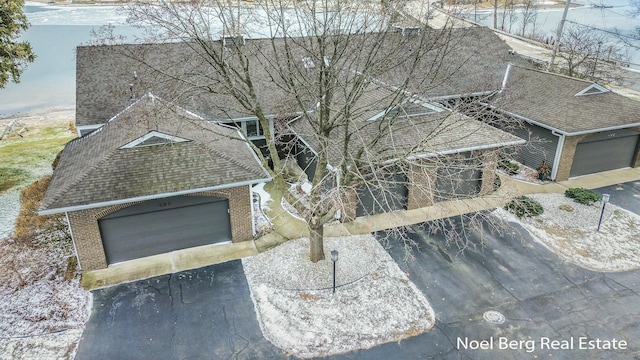 exterior space featuring aphalt driveway, brick siding, a shingled roof, and an attached garage