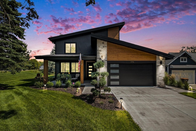 modern home with a front yard, concrete driveway, and an attached garage