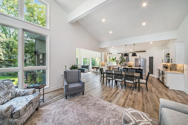 living area featuring baseboards, beamed ceiling, light wood-type flooring, high vaulted ceiling, and recessed lighting