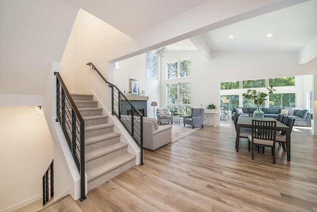 living room with high vaulted ceiling, light wood-style flooring, recessed lighting, a premium fireplace, and stairs