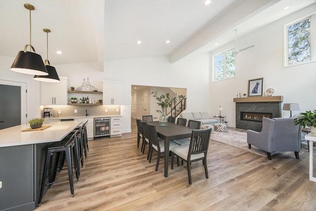 dining space with wine cooler, indoor wet bar, light wood finished floors, and a premium fireplace