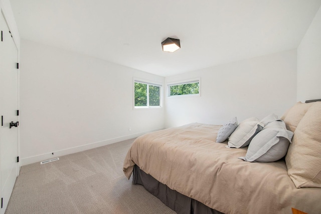 bedroom featuring baseboards, visible vents, and light colored carpet