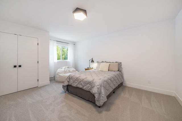 bedroom featuring baseboards, a closet, and light colored carpet