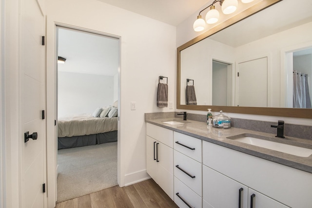 ensuite bathroom featuring double vanity, a sink, ensuite bathroom, and wood finished floors