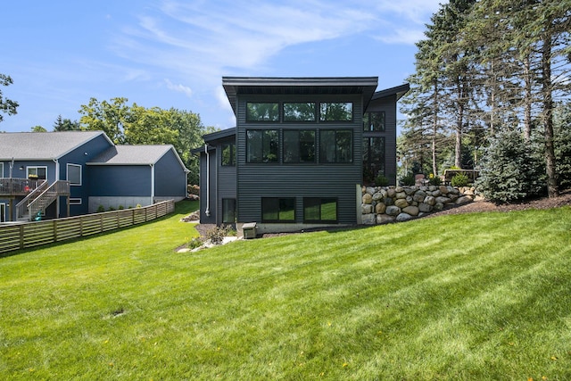 back of property featuring a lawn and fence