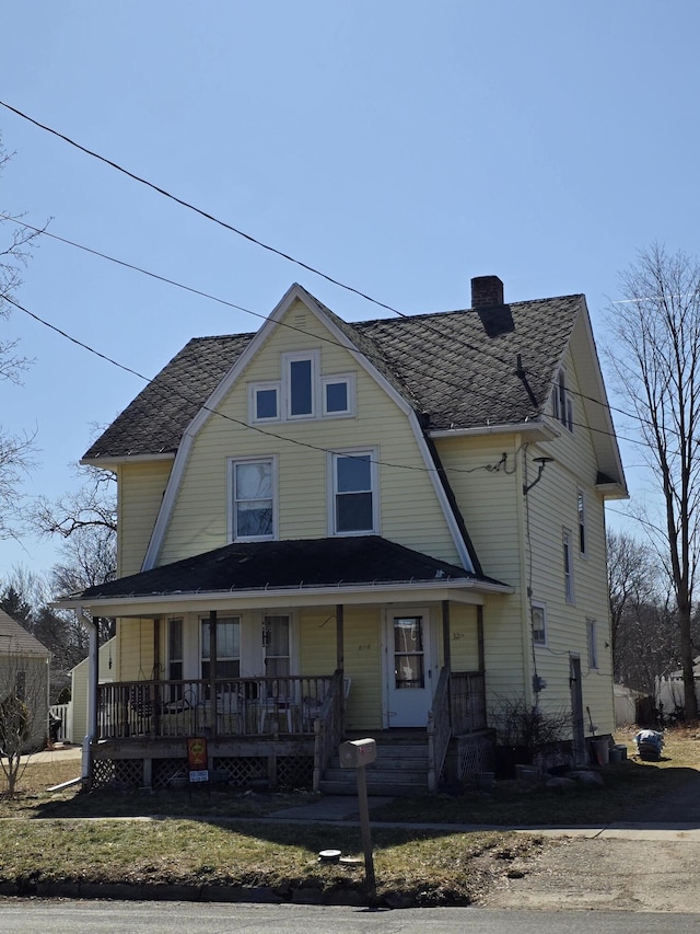 view of front facade featuring a gambrel roof, a porch, and a chimney