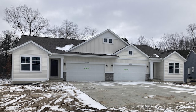 view of front of property with concrete driveway, stone siding, an attached garage, and a shingled roof