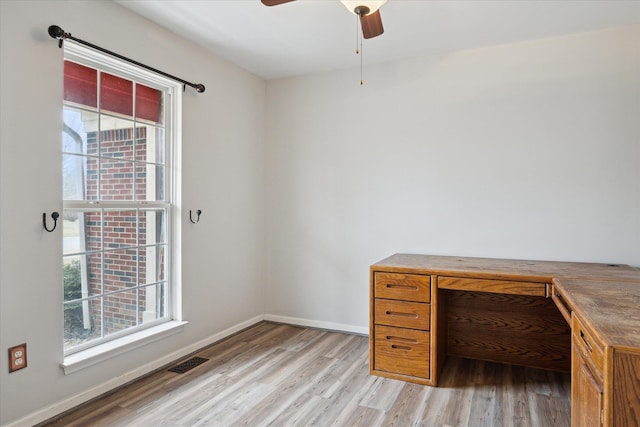 unfurnished office featuring light wood-type flooring, baseboards, visible vents, and ceiling fan