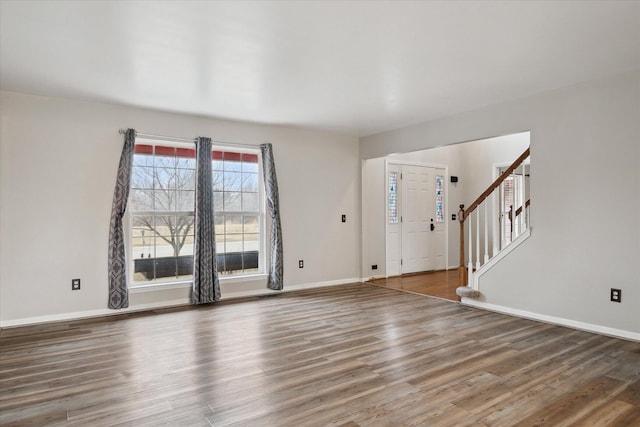 foyer entrance featuring baseboards, stairway, and wood finished floors