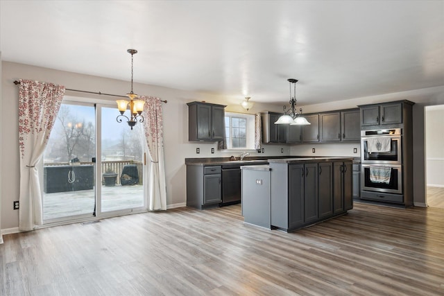 kitchen with a center island, decorative light fixtures, stainless steel appliances, wood finished floors, and baseboards