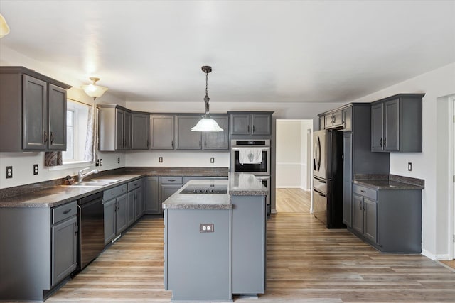 kitchen featuring a sink, black appliances, a kitchen island, and light wood-style flooring