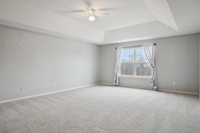 unfurnished room featuring a ceiling fan, a tray ceiling, baseboards, and carpet