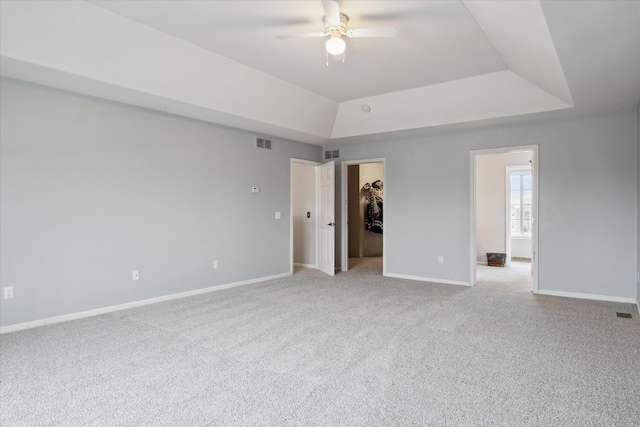 spare room with a raised ceiling, visible vents, and baseboards