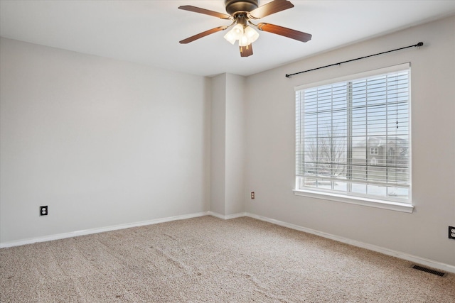 carpeted spare room featuring ceiling fan, visible vents, and baseboards