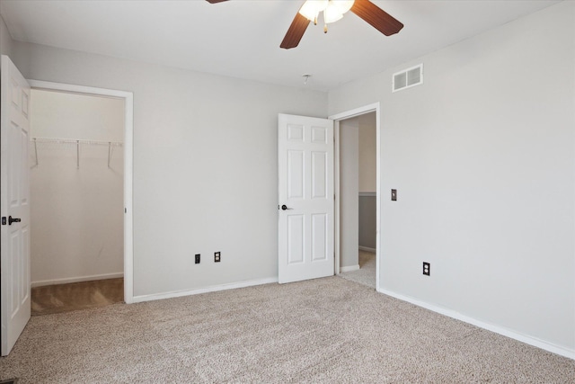 unfurnished bedroom with carpet floors, visible vents, a spacious closet, and baseboards