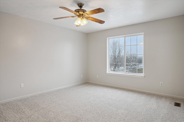 empty room with a ceiling fan, visible vents, light carpet, and baseboards