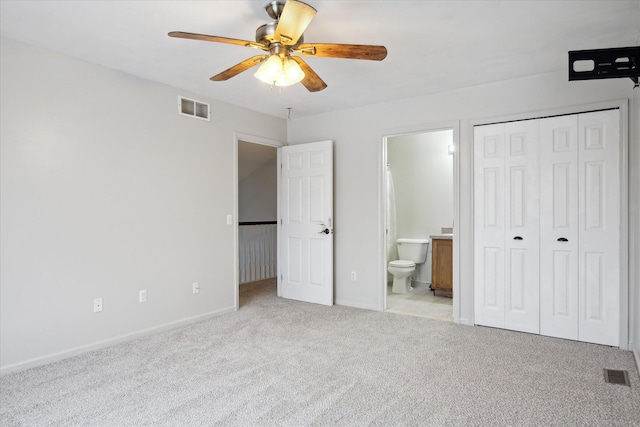 unfurnished bedroom featuring a closet, ensuite bath, carpet flooring, and visible vents