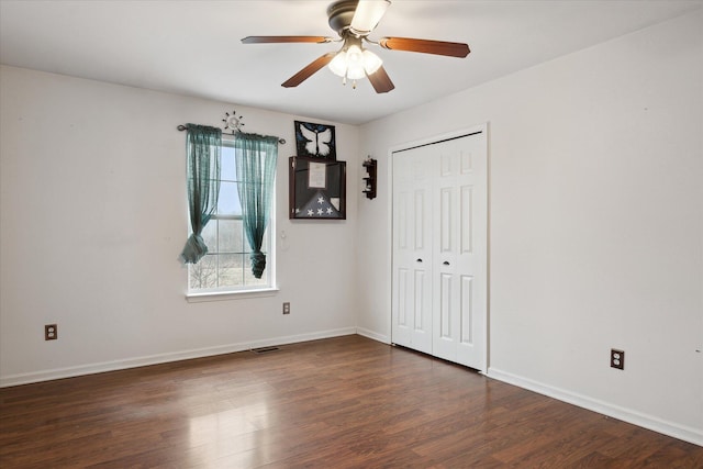 empty room featuring ceiling fan, dark wood-type flooring, visible vents, and baseboards