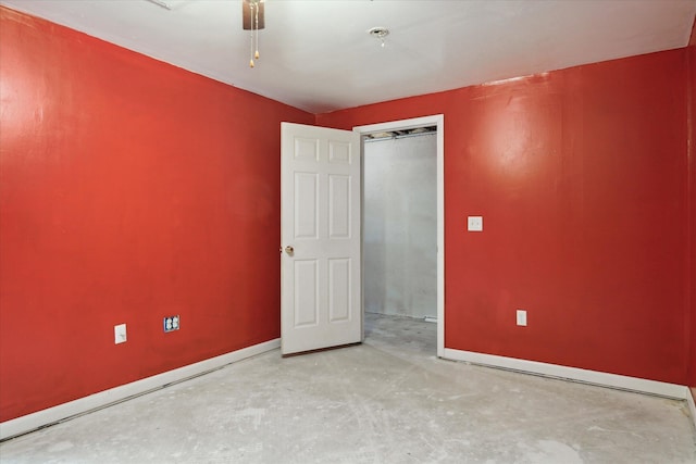 spare room featuring baseboards and unfinished concrete flooring