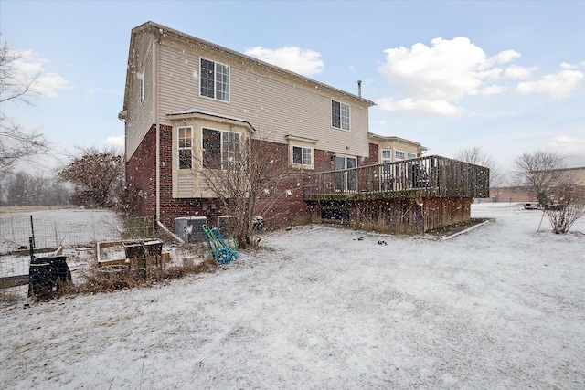 snow covered property featuring brick siding and a deck