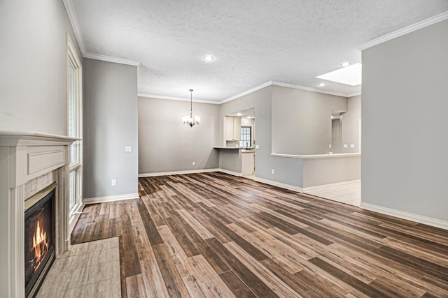 unfurnished living room featuring baseboards, wood finished floors, a textured ceiling, a fireplace, and a chandelier