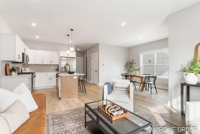 living area featuring recessed lighting, light wood-type flooring, and baseboards