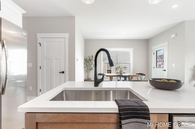 kitchen featuring light stone counters, freestanding refrigerator, and a sink