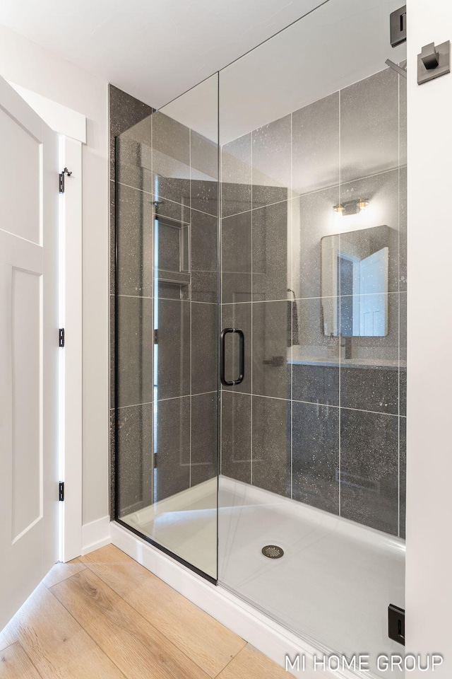 bathroom featuring wood finished floors and a shower stall