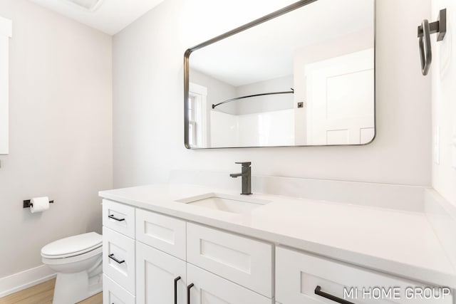 full bath featuring toilet, wood finished floors, baseboards, walk in shower, and vanity