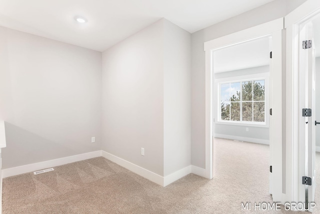 carpeted spare room with visible vents and baseboards