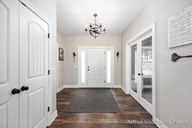 foyer with a chandelier, dark wood-style flooring, and baseboards