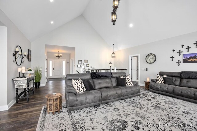 living room with dark wood-type flooring, high vaulted ceiling, baseboards, and an inviting chandelier