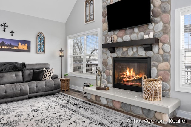 living room featuring a fireplace, baseboards, vaulted ceiling, and wood finished floors