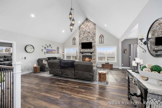 living room featuring baseboards, high vaulted ceiling, wood finished floors, and a stone fireplace