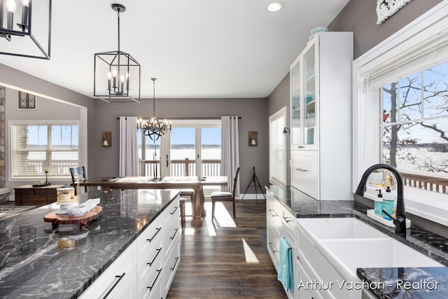 kitchen featuring a healthy amount of sunlight, a notable chandelier, glass insert cabinets, and a sink