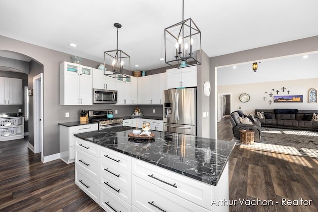 kitchen featuring arched walkways, stainless steel appliances, dark wood-type flooring, glass insert cabinets, and open floor plan