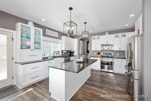 kitchen with stainless steel appliances, dark wood-type flooring, a kitchen island, white cabinets, and glass insert cabinets