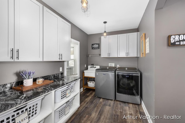 washroom featuring cabinet space, baseboards, dark wood-style flooring, independent washer and dryer, and a sink