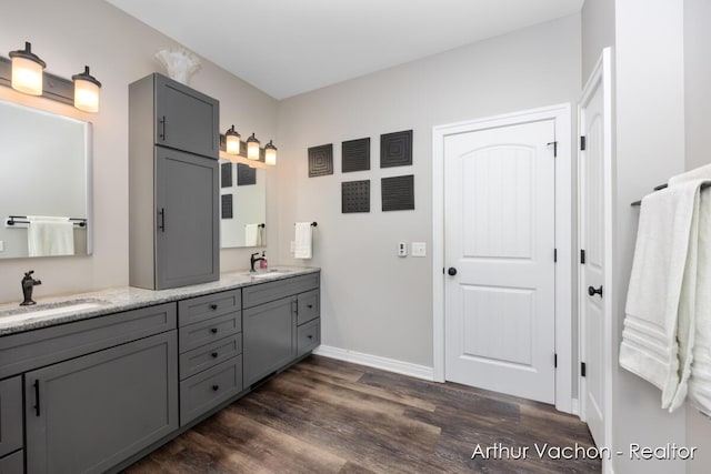 full bath featuring double vanity, baseboards, a sink, and wood finished floors