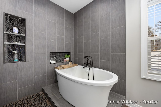 bathroom with a freestanding tub and tile walls