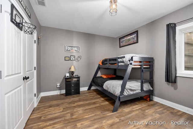 bedroom with visible vents, baseboards, and wood finished floors