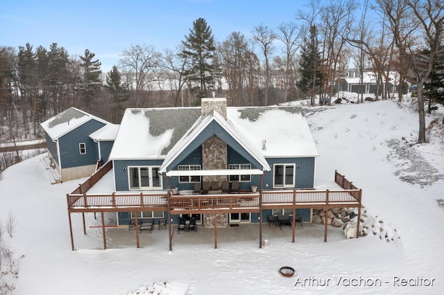 snow covered property featuring a chimney and a wooden deck