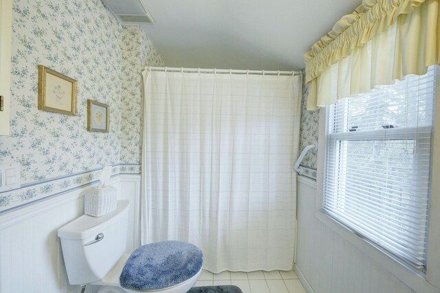 full bath featuring wallpapered walls, a shower with shower curtain, toilet, wainscoting, and tile patterned flooring